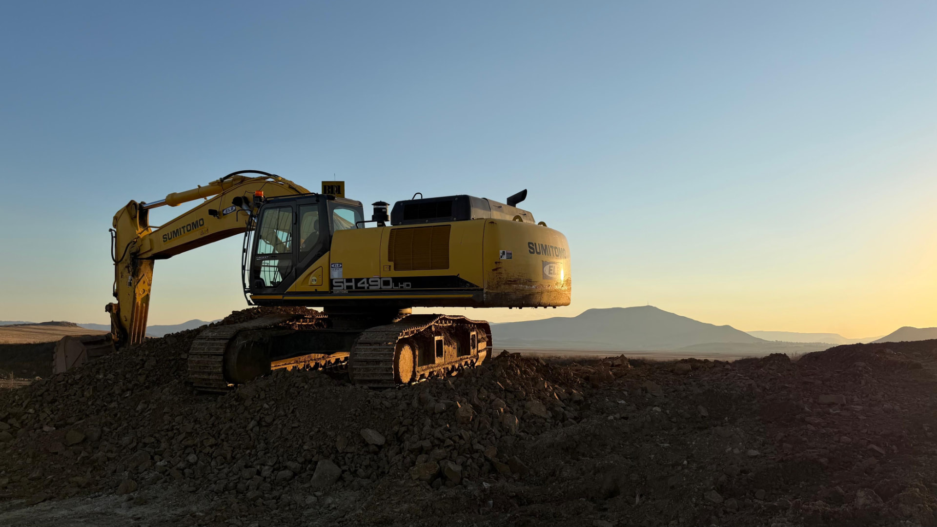 Yellow Sumitomo excavator working at the Umvubu Crushers quarry near Kokstad at dawn